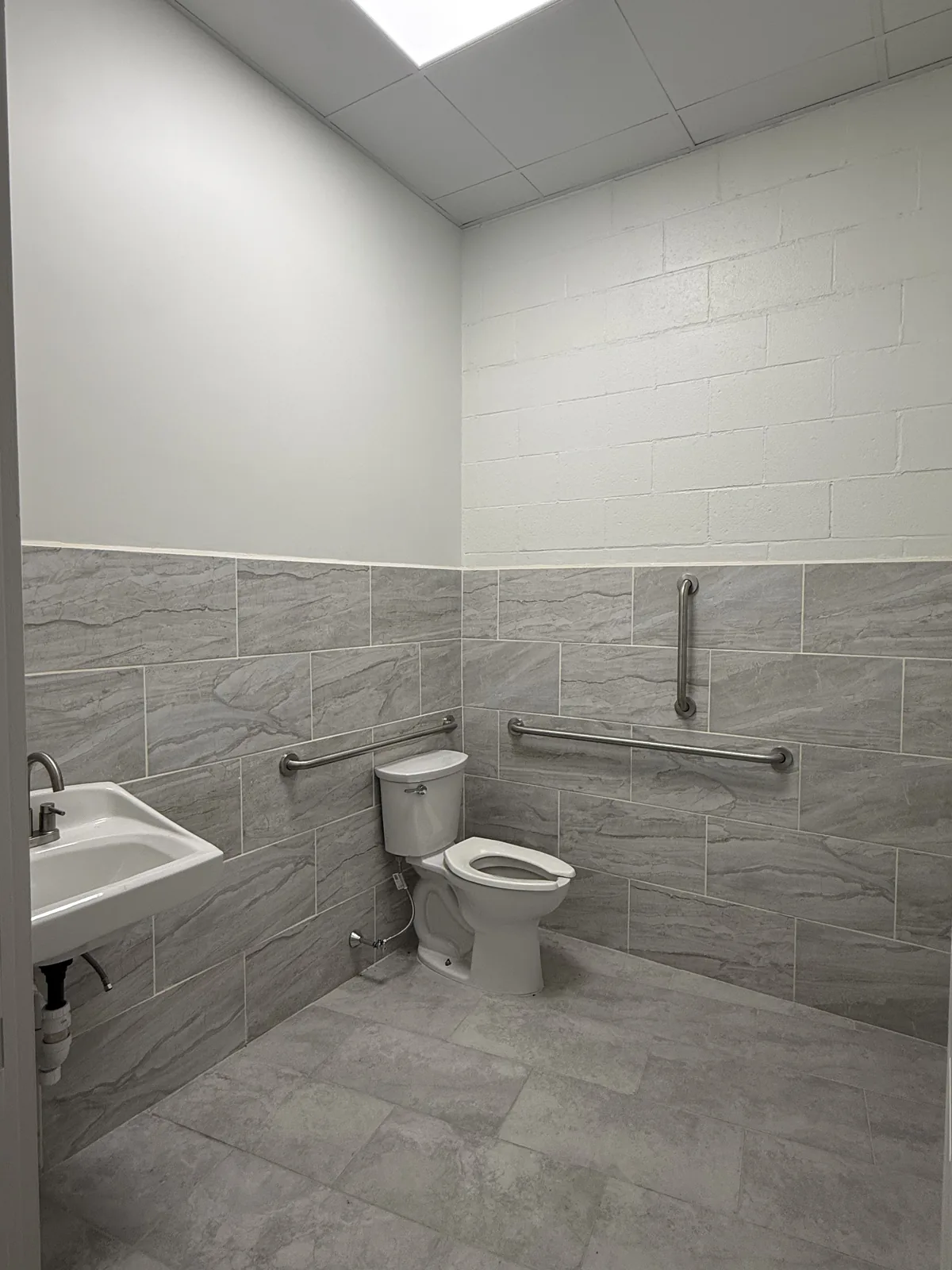 Accessible shared restroom with grab bars, new tile and new fixtures