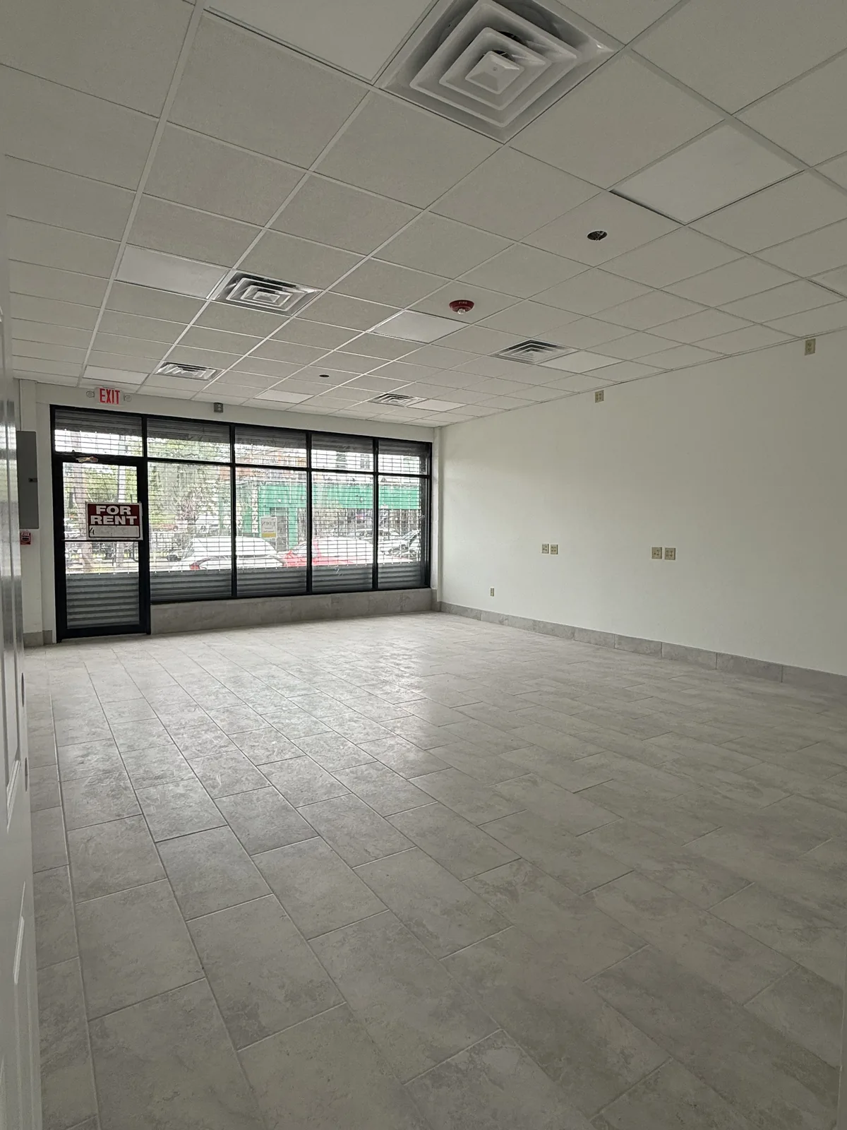 Unit 2 looking toward the glass storefront on Chalkstone Ave — new gray tile floor, painted walls and drop ceiling with panel lights